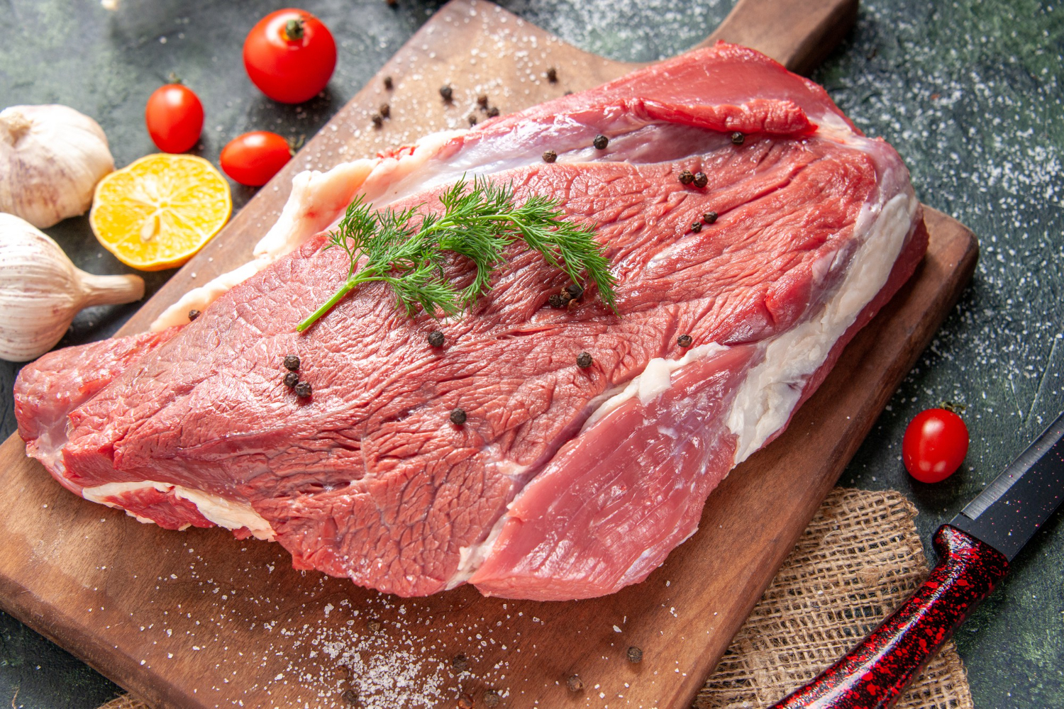front-view-fresh-raw-red-meat-wooden-cutting-board-nude-color-towel-lemon-garlic-mixed-color-background