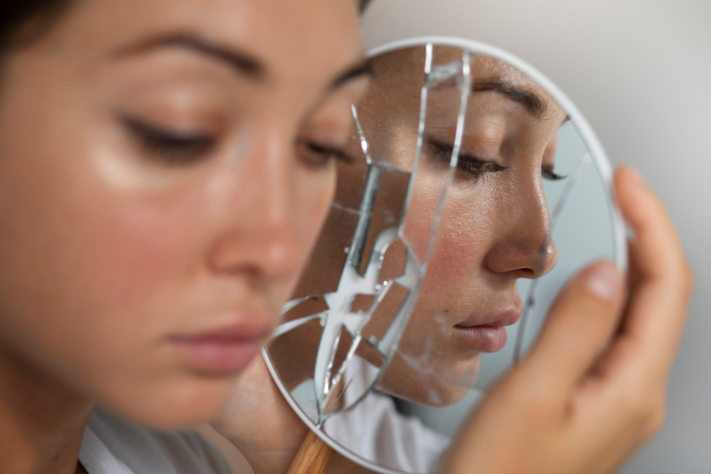portrait-young-woman-with-low-self-esteem-looking-hand-held-mirror