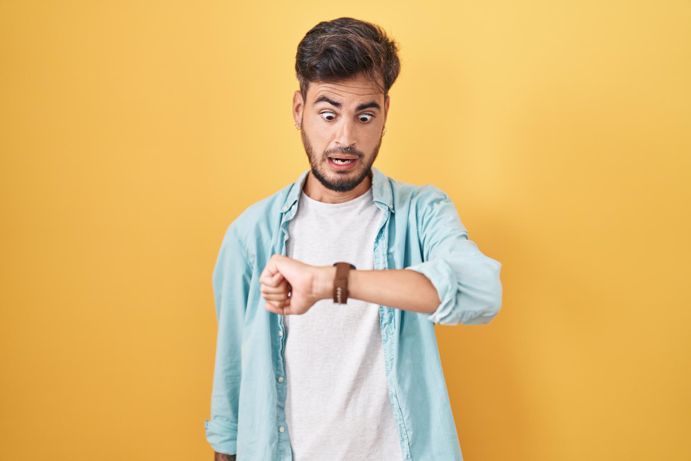 young-hispanic-man-with-tattoos-standing-yellow-background-looking-watch-time-worried-afraid-getting-late