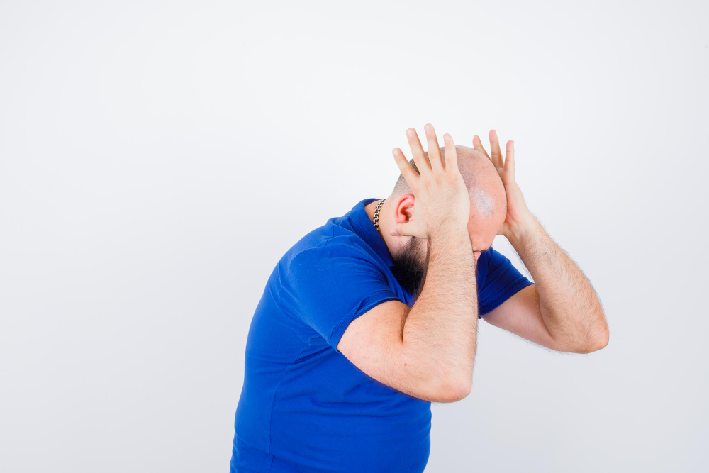 young-man-holding-hands-head-while-bending-forward-blue-shirt-looking-impatient
