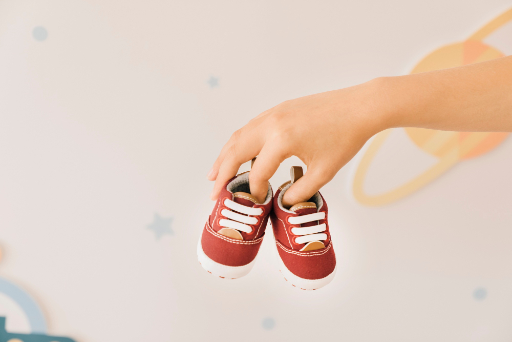 newborn-concept-with-fingers-holding-shoes